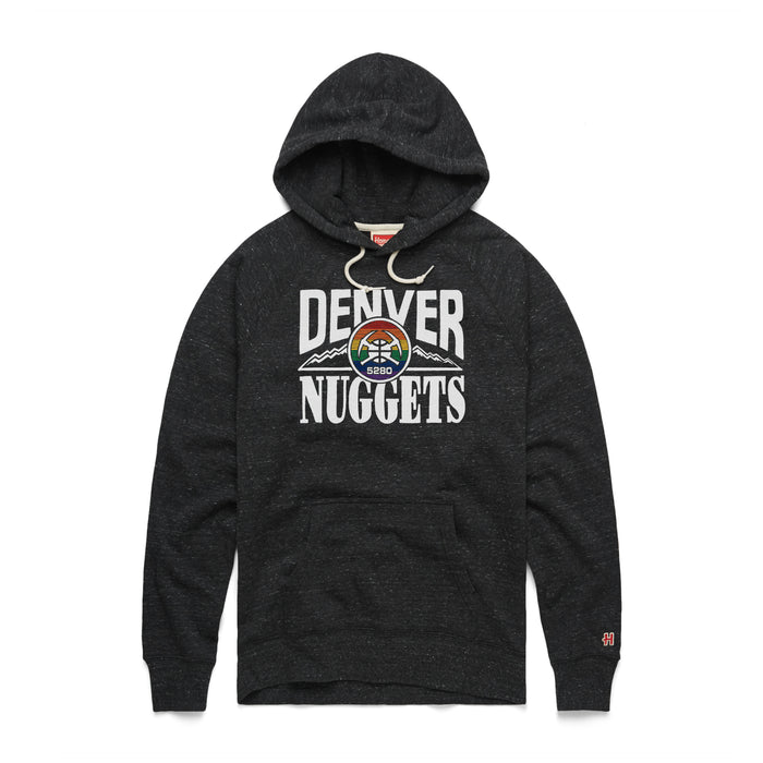 A heather charcoal black pullover hoody featuring a large retro Denver Nuggets graphic on the center chest. The word 'DENVER' arcs across the top and 'NUGGETS' sits straight below in bold white lettering. Framed between the words is a circular emblem with a rainbow-striped background and crossed white pickaxes over a basketball, flanked by horizontal jagged mountain peaks. The hoody includes cream-colored drawstrings, a front kangaroo pocket, and a small orange circular brand logo stitched on th