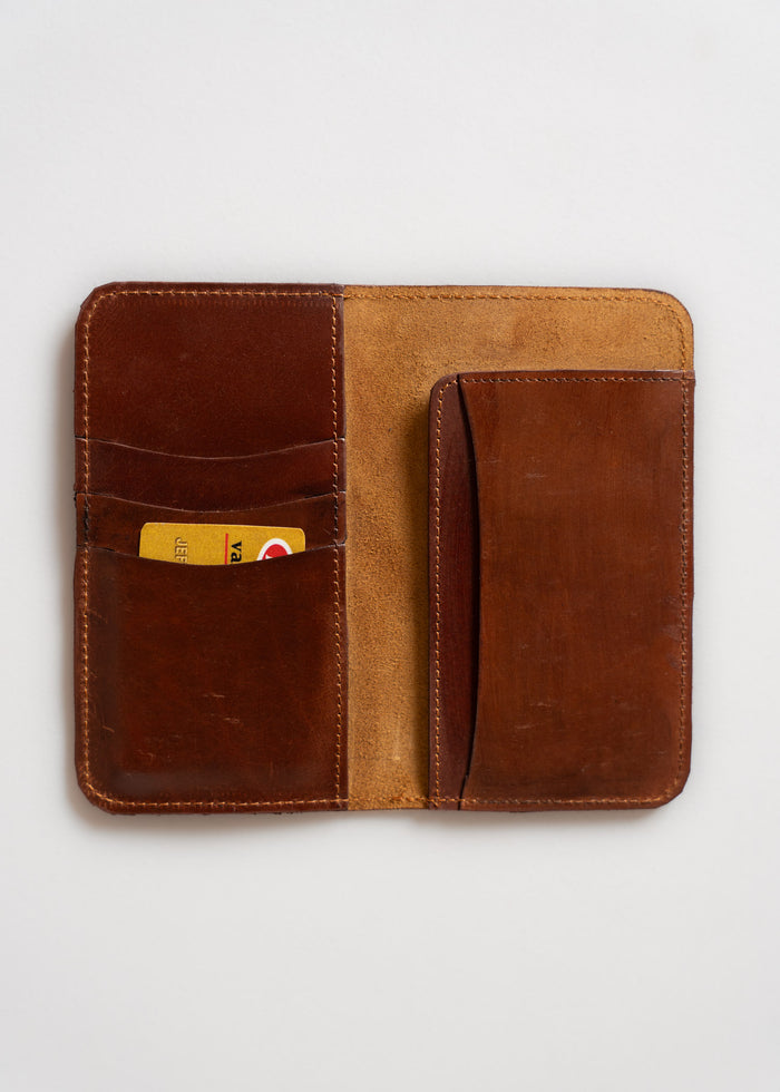 Open brown leather wallet with card slots, holding a yellow card, on a white background. Simple and elegant design.