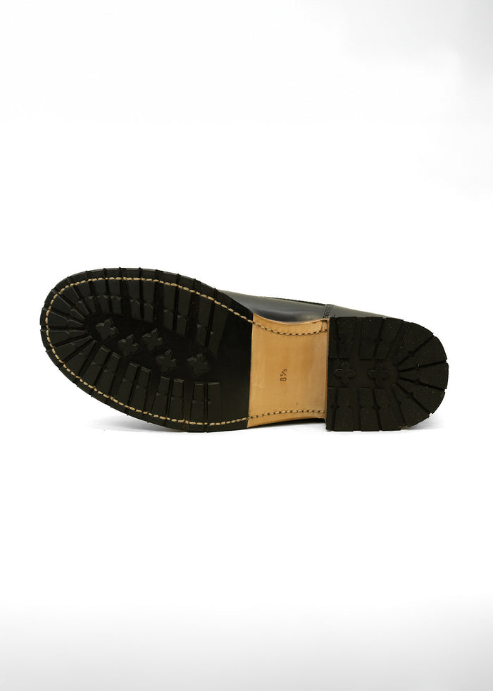 Black boot sole with rugged tread pattern, beige midsole, and visible stitching on a white background. Size 8.5 marked.