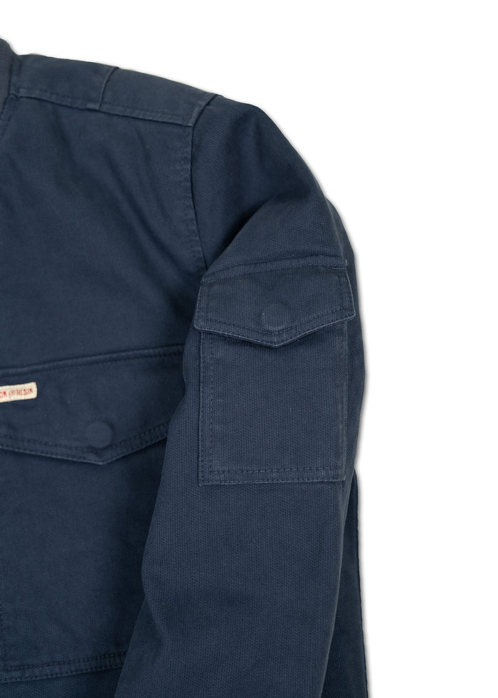 Close-up of a navy blue jacket sleeve with a buttoned flap pocket, showcasing the fabric texture and stitching details.