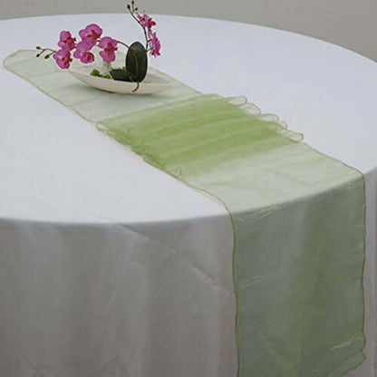 Green table runner on a white table with decorative flowers.