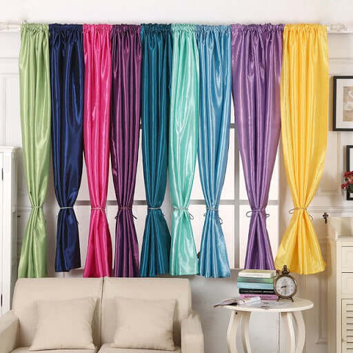 Colorful curtain panels in various shades hanging in a bright room.