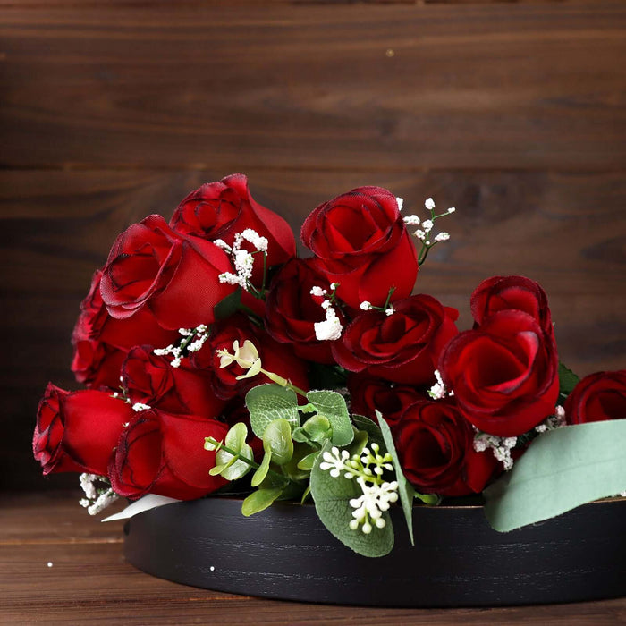 Red silk roses arranged in a decorative black bowl.