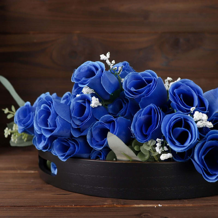 Blue velvet roses in a black decorative bowl against a wooden background.
