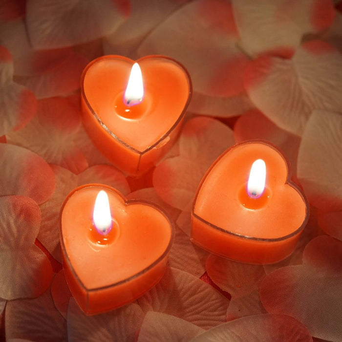 Heart-shaped candles glowing on rose petal background.