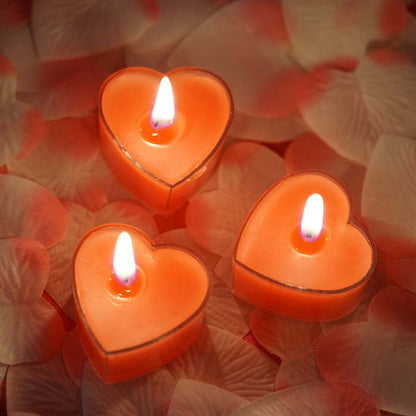 Heart-shaped candles glowing on rose petal background.