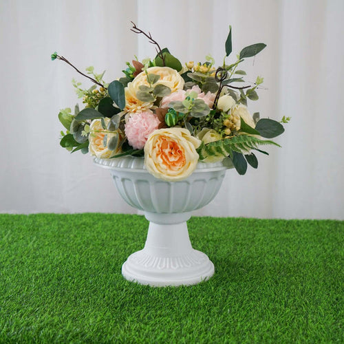 Floral arrangement in a white urn on green grass.