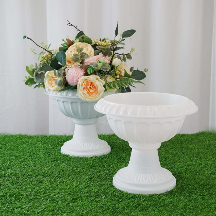 White decorative planters with floral arrangements on green grass backdrop.