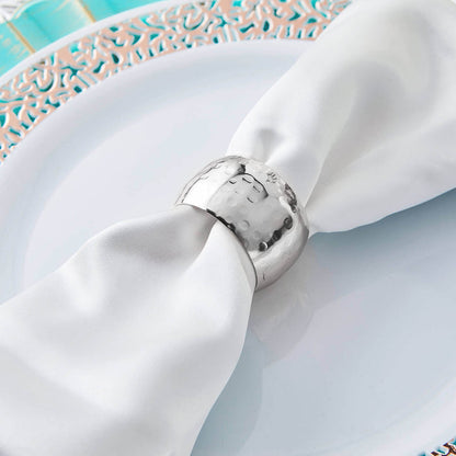 Silver napkin ring on a white silk napkin atop an elegant plate.