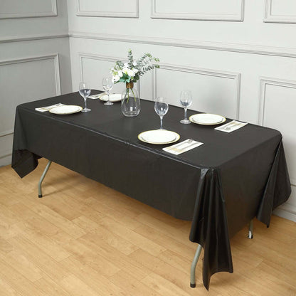 Elegant black tablecloth draped over a table set for dining with plates and glasses.