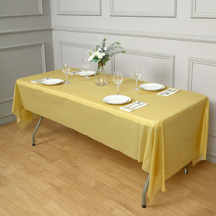 Yellow tablecloth draped over a dining table set with plates and glasses.
