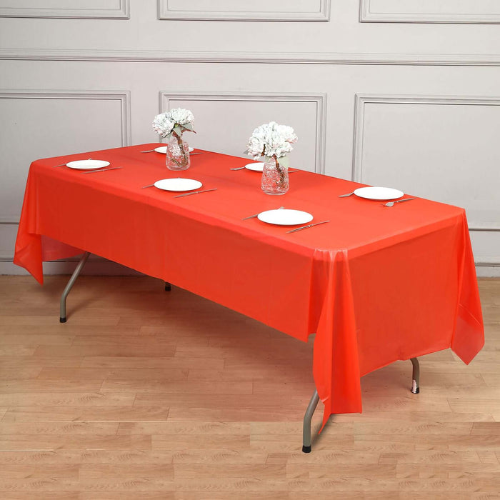 Red tablecloth draped over a table set with plates and flowers.