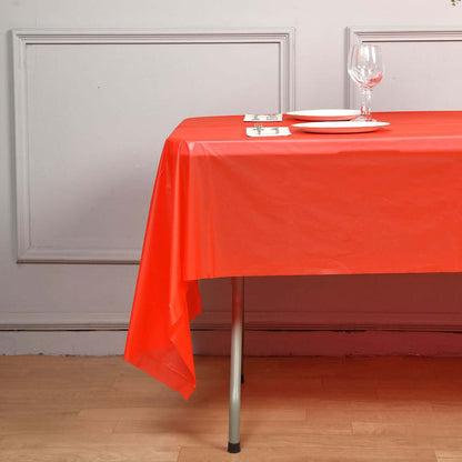 Red plastic tablecloth draped over a table set with plates and a wine glass.