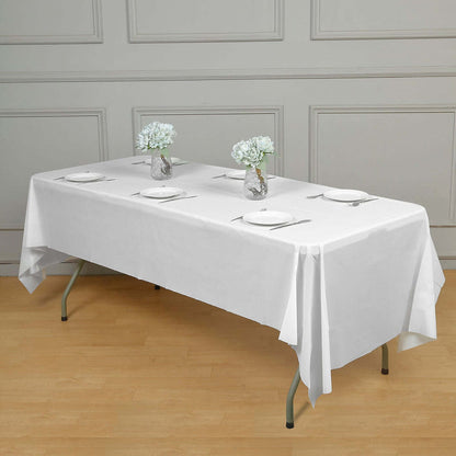 White tablecloth draped over a table set for dining with flower vases.