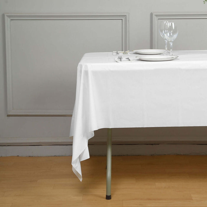 White tablecloth draped over a table set for dining.