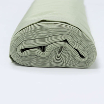 Rolled sage green fabric on a plain backdrop