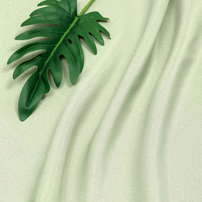 Green fabric with a tropical leaf on top, showcasing texture and drape.