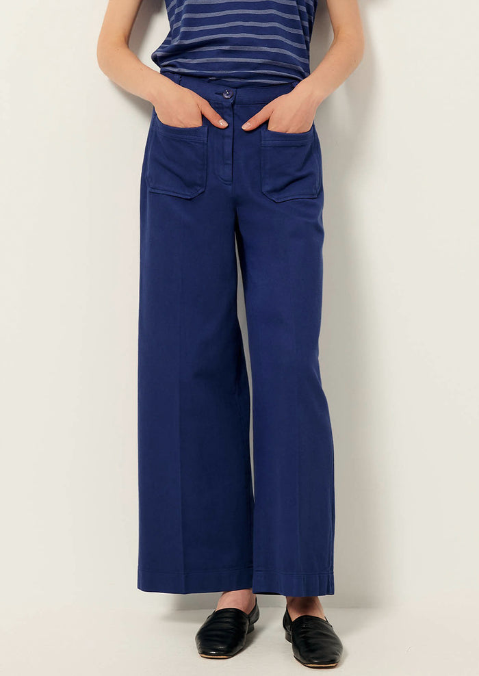 A person wearing a pair of blue wide leg pants with front patch pockets.