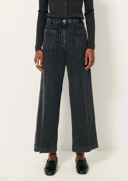 A person wearing a pair of wide leg jeans in charcoal pinstripe denim.
