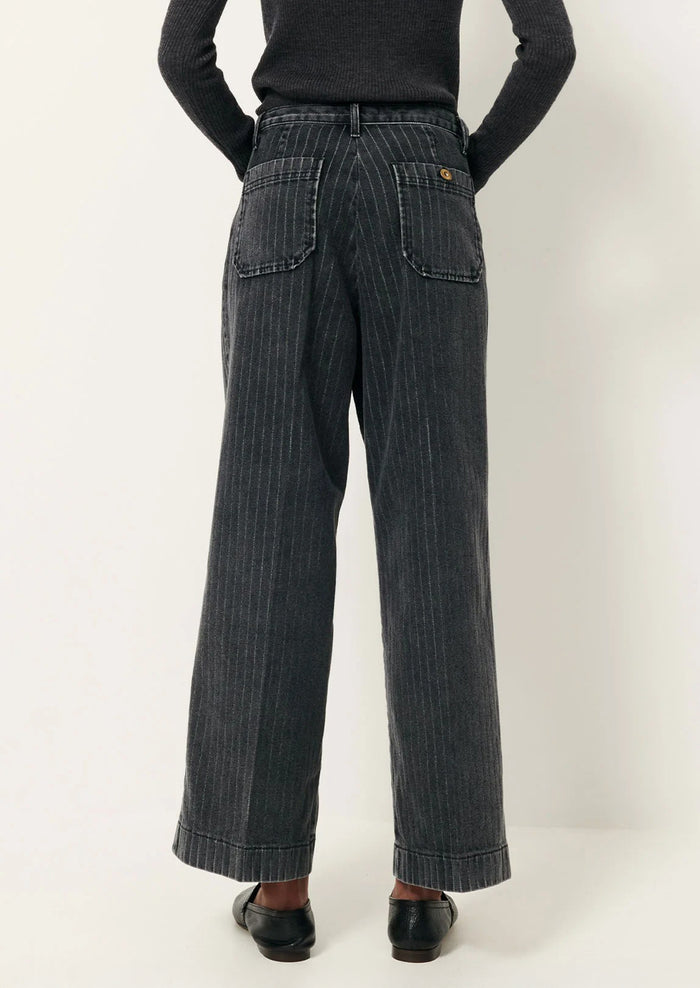 A person wearing a pair of wide leg jeans in charcoal pinstripe denim.
