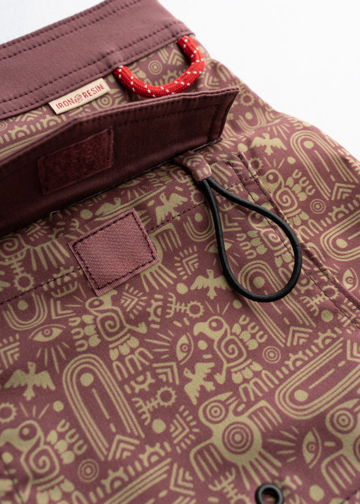 Close-up of a patterned fabric bag with a red loop and Iron & Resin label, featuring abstract designs in earthy tones.