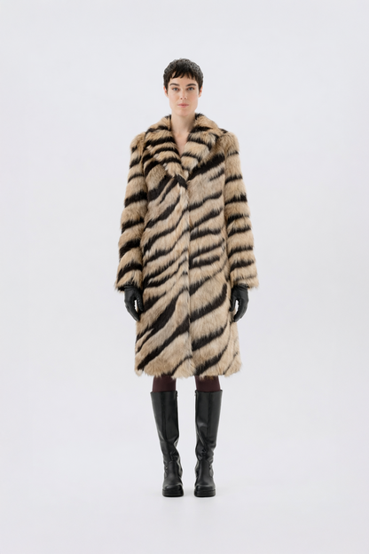 Tan and black tiger-stripe faux fur coat with notch lapel and full-length fit, worn over black gloves and knee-high boots, front view