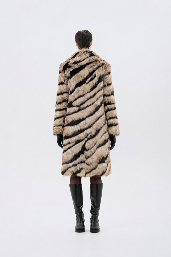Tan and black tiger-stripe faux fur coat with notch lapel and full-length fit, worn over black gloves and knee-high boots, back view