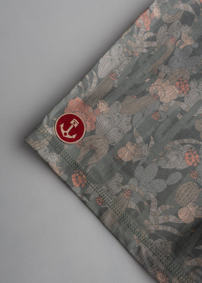 Fabric with a cactus pattern and a red anchor logo on the corner, set against a neutral background, highlighting the design.