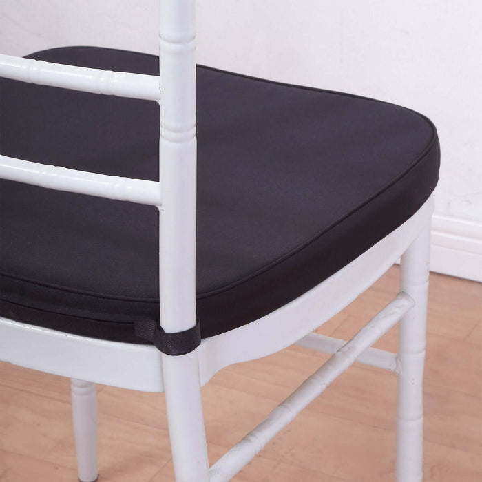 Black chair cushion on a white chair against a plain background.