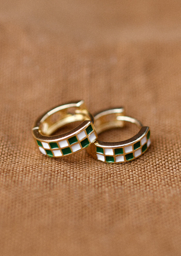 A pair of gold hoop earrings with green and white enamel checker pattern.