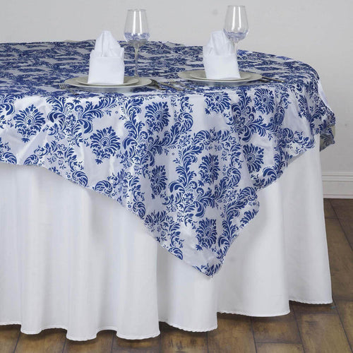Elegant blue and white damask tablecloth draped over a round table setting.