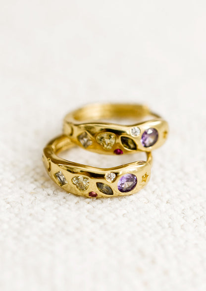 A pair of gold huggie hoops with embedded crystals in a mix of colors and shapes.
