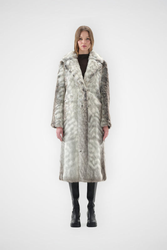 Grey and cream snow leopard faux fur coat with notch lapel and full-length, relaxed fit, worn over black knee-high boots, front view