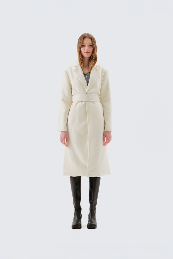 Cream faux wool coat with notch lapel, self-belt at the waist, and raw-edge trim, worn full-length over black boots, front view