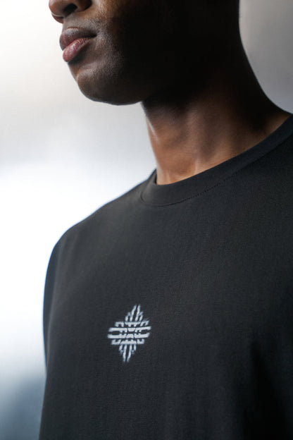 Person wearing a black t-shirt with a white logo on a blurred background