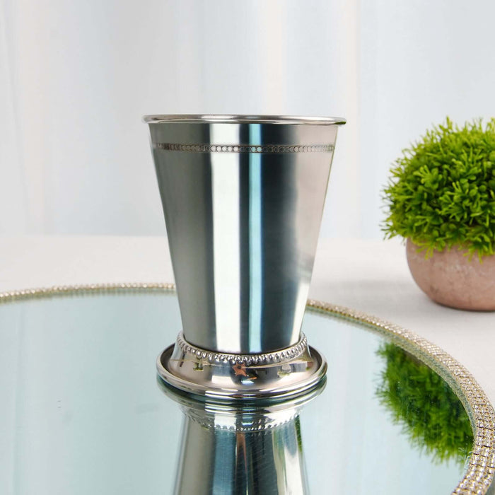 Silver decorative cup with a polished finish on a reflective surface.