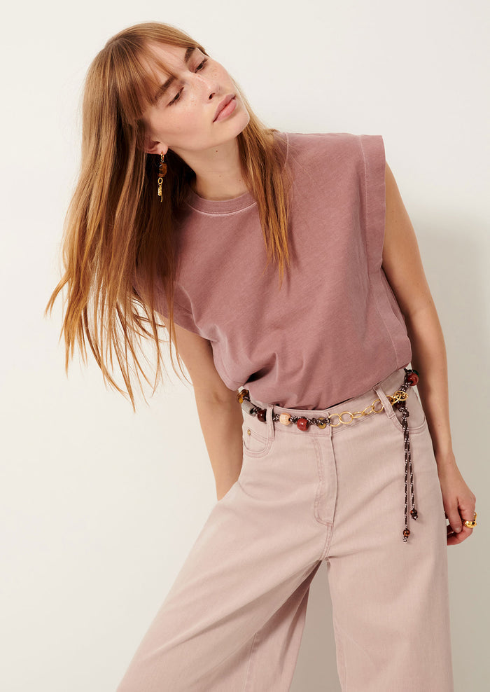 A person wearing a muscle tee in muted mauve color.