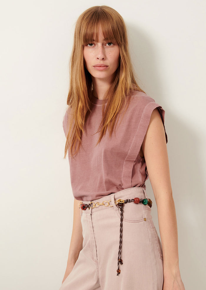 A person wearing a muscle tee in muted mauve color.