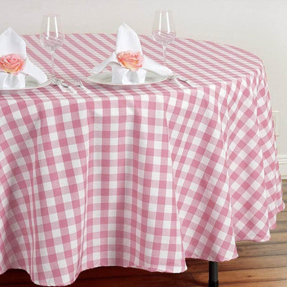 Pink gingham tablecloth with white napkins and glasses on a wooden table.