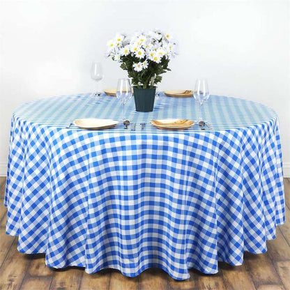 Blue and white checkered tablecloth draped over a round table with flowers and dinnerware.