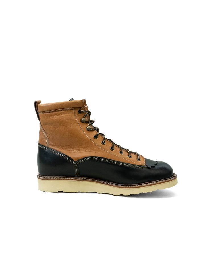 Brown and black leather boot with white sole, featuring detailed stitching and metal eyelets, isolated on a white background.