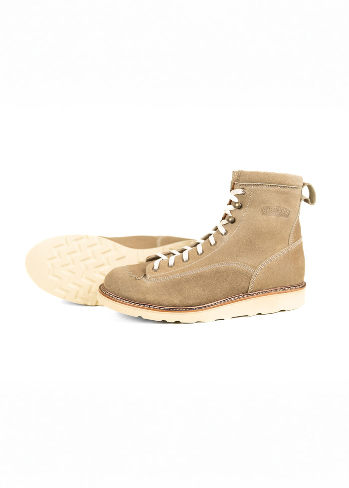 Tan suede boots with white laces and rugged soles, one upright and one on its side, showcasing the tread pattern.