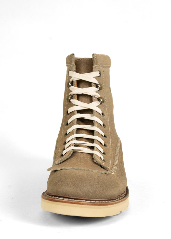 Tan suede boot with white laces on a white background, showcasing rugged design and sturdy sole for outdoor wear.
