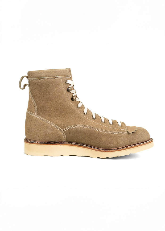 Tan suede lace-up boot with a cream sole, side view. Features detailed stitching and a pull tab at the back for easy wear.