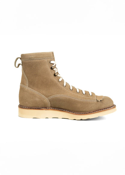 Tan suede lace-up boot with a cream sole, side view. Features detailed stitching and a pull tab at the back for easy wear.