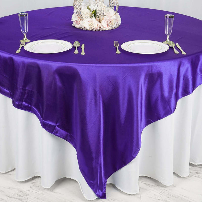 Purple satin tablecloth on a round table set for dining.