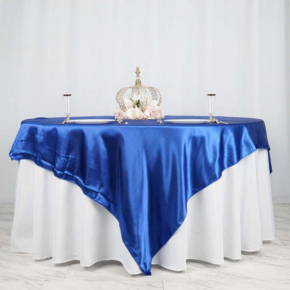Elegant blue satin tablecloth draped over a round table with a crown centerpiece.