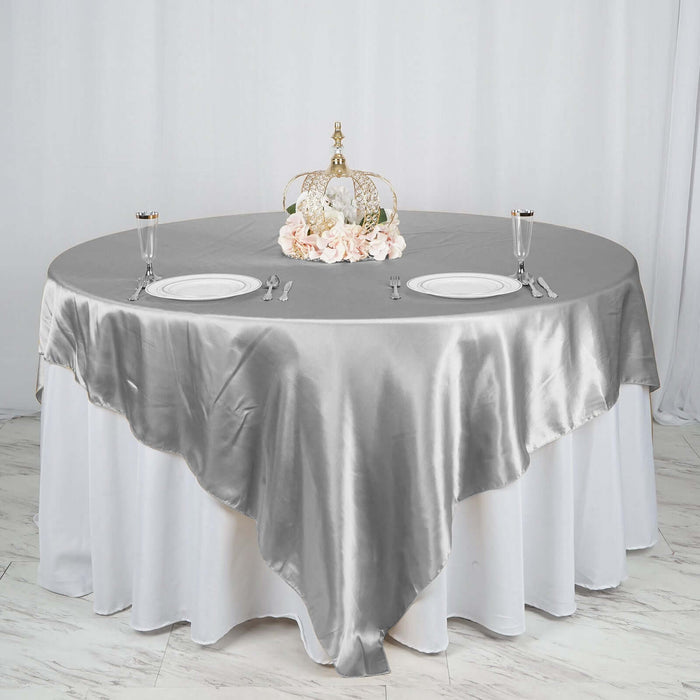 Elegant grey satin tablecloth on round table with decorative centerpiece.