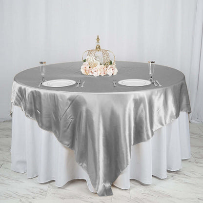 Elegant grey satin tablecloth on round table with decorative centerpiece.