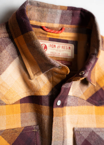 Close-up of a yellow and brown plaid shirt with a visible Iron & Resin label, highlighting its texture and button details.